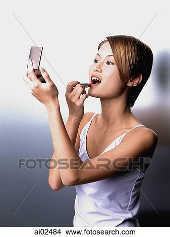 Woman applying lipstick, looking in compact mirror View Large Photo Image Picture - Woman applying lipstick, looking in compact mirror. Fotosearch