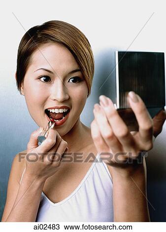 Woman applying lipstick, looking in compact mirror View Large Photo Image Stock Image - Woman applying lipstick, looking in compact mirror. Fotosearch