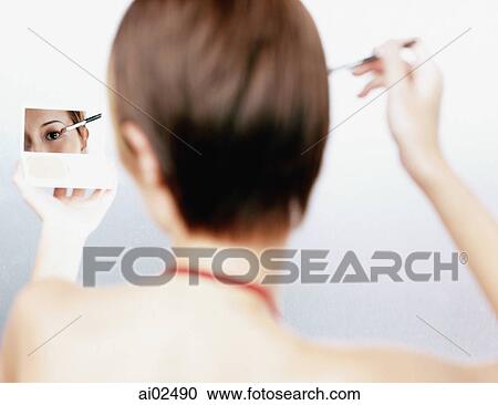 Woman applying make-up, looking in compact mirror, rear view View Large Photo Image Stock Image - Woman applying make-up, looking in compact mirror, rear view. Fotosearch