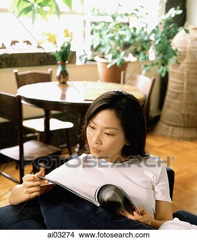 Woman at home reading a magazine, dining room in background View Large Photo Image Picture - Woman at home reading a magazine, dining room in background. Fotosearch