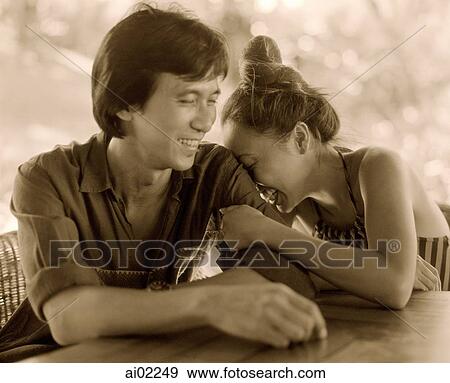 Stock Photo - Woman buries face in man's arm, laughing. Fotosearch