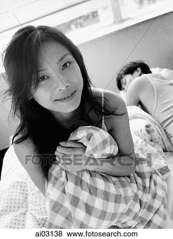 Woman clutching pillow, man sleeping in background, portrait View Large Photo Image Stock Photo - Woman clutching pillow, man sleeping in background, portrait. Fotosearch