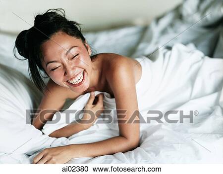Woman covered in sheet laughing in bed. View Large Photo Image Stock Image - Woman covered in sheet laughing in bed.. Fotosearch