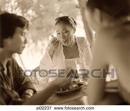 Stock Photo - Woman eating with friends. Fotosearch