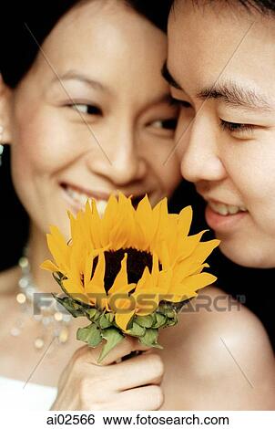 Woman holding a flower with smiling man View Large Photo Image Stock Photograph - Woman holding a flower with smiling man. Fotosearch