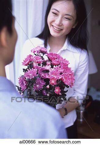 Woman holding bouquet of flowers, man in foreground View Large Photo Image Stock Photograph - Woman holding bouquet of flowers, man in foreground. Fotosearch