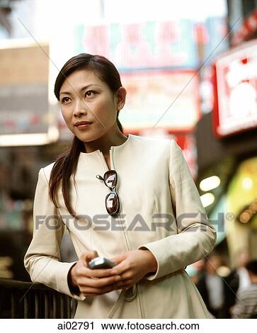 Woman holding cellular phone in busy street. View Large Photo Image Stock Image - Woman holding cellular phone in busy street.. Fotosearch