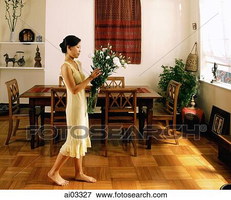 Woman holding flowers, walking in dining room View Large Photo Image Stock Photo - Woman holding flowers, walking in dining room. Fotosearch