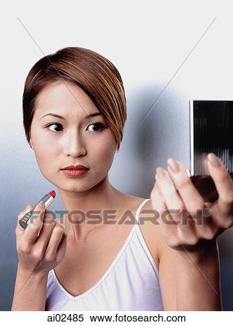 Woman holding lipstick, looking in compact mirror View Large Photo Image Stock Photography - Woman holding lipstick, looking in compact mirror. Fotosearch