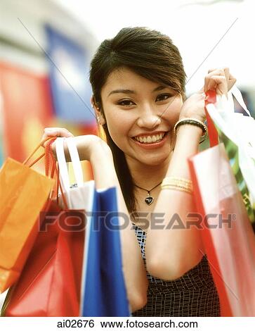 Stock Photograph - Woman holding shopping bags, smiling, portrait.. Fotosearch