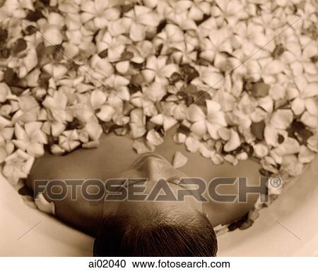 Stock Image - Woman in bathtub with flower petals, high angle. Fotosearch