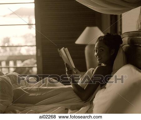 Woman in bed holding book View Large Photo Image Stock Photo - Woman in bed holding book. Fotosearch