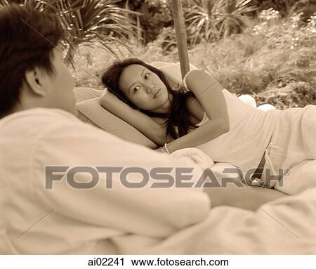 Stock Image - Woman lying down looking at man. Fotosearch