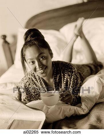 Woman lying on bed holding cup View Large Photo Image Stock Photography - Woman lying on bed holding cup. Fotosearch