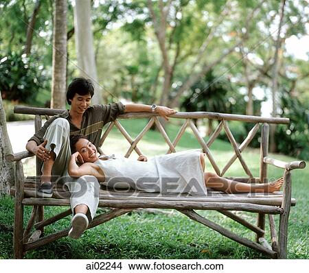 Woman lying on bench with head on man's lap, outdoors View Large Photo Image Picture - Woman lying on bench with head on man's lap, outdoors. Fotosearch