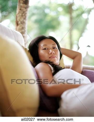 Woman lying on sofa outdoors, palm trees behind View Large Photo Image Stock Photo - Woman lying on sofa outdoors, palm trees behind. Fotosearch