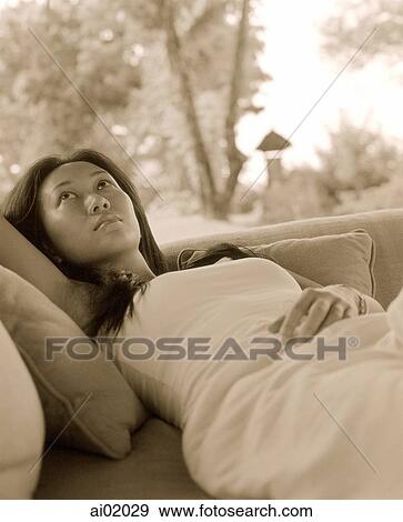 Woman lying on sofa outdoors, palm trees behind View Large Photo Image Stock Photo - Woman lying on sofa outdoors, palm trees behind. Fotosearch