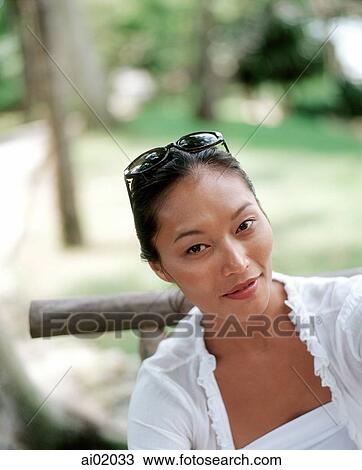 Stock Image - Woman relaxing outdoors, smiling. Fotosearch