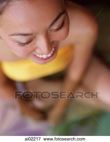 Stock Photo - Woman sitting in swimming pool, smiling, top view. Fotosearch