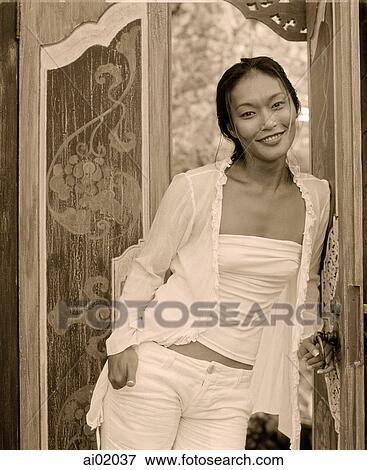 Stock Photo - Woman standing in doorway, smiling. Fotosearch
