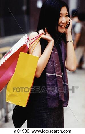 Woman talking on cellular phone, holding shopping bags View Large Photo Image Stock Photograph - Woman talking on cellular phone, holding shopping bags. Fotosearch