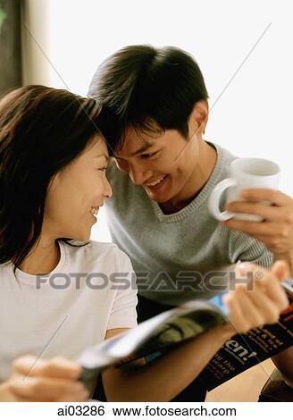 Stock Photograph - Woman with magazine talking with man holding cup. Fotosearch