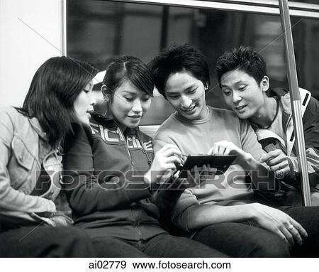 Young adults in train looking at PDA. View Large Photo Image Stock Photo - Young adults in train looking at PDA.. Fotosearch