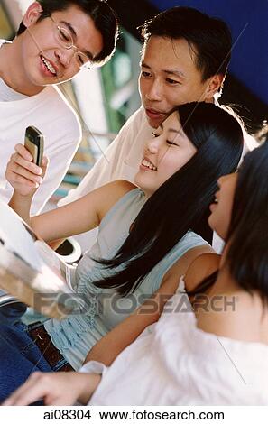 Young adults looking at mobile phone, smiling. View Large Photo Image Picture - Young adults looking at mobile phone, smiling.. Fotosearch
