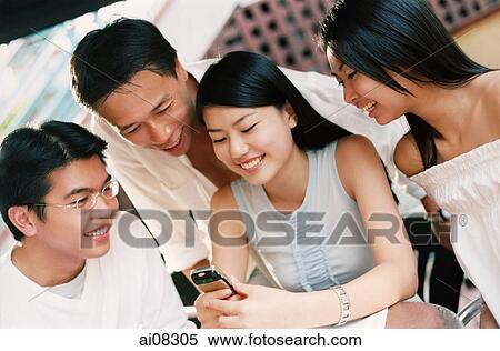 Stock Photography - Young adults looking at mobile phone, smiling.. Fotosearch