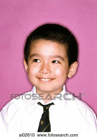 Stock Image - Young boy dressed in tie and shirt, smiling, purple background.. Fotosearch
