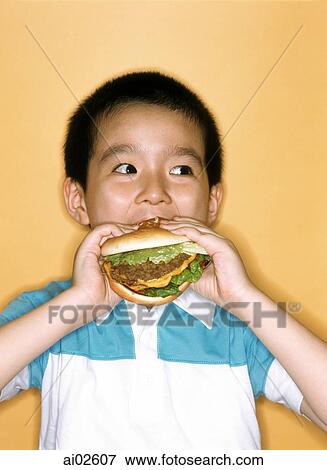 Young boy eating large hamburger, yellow background. View Large Photo Image Stock Photo - Young boy eating large hamburger, yellow background.. Fotosearch