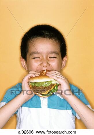 Young boy eating large hamburger, yellow background. View Large Photo Image Stock Photograph - Young boy eating large hamburger, yellow background.. Fotosearch