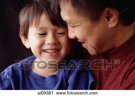 Stock Image - Young boy held by father, laughing. Fotosearch