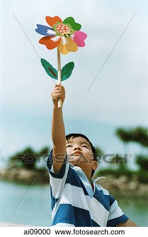 Young boy holding pin-wheel flower View Large Photo Image Stock Image - Young boy holding pin-wheel flower. Fotosearch