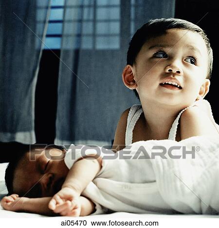 Young boy lying on bed behind sleeping baby View Large Photo Image Stock Image - Young boy lying on bed behind sleeping baby. Fotosearch
