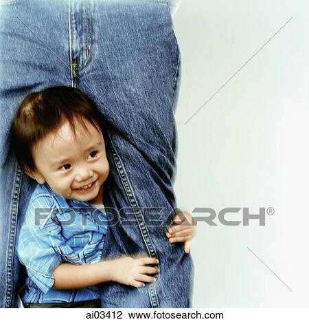 Stock Image - Young boy peeking between the legs of his father. Fotosearch