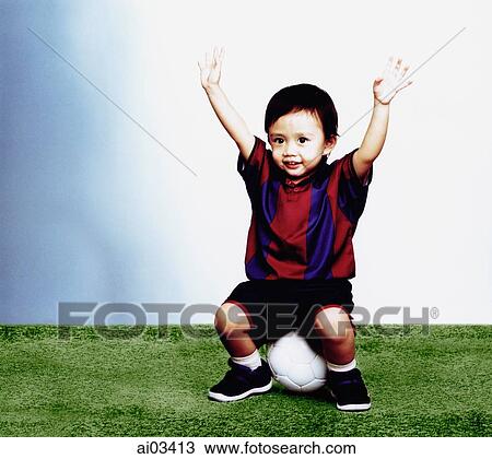 Young boy sitting on soccer ball with arms in the air View Large Photo Image Stock Image - Young boy sitting on soccer ball with arms in the air. Fotosearch
