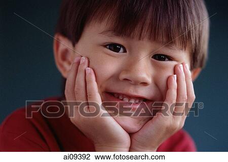 Stock Image - Young boy with hands on chin smiling. Fotosearch