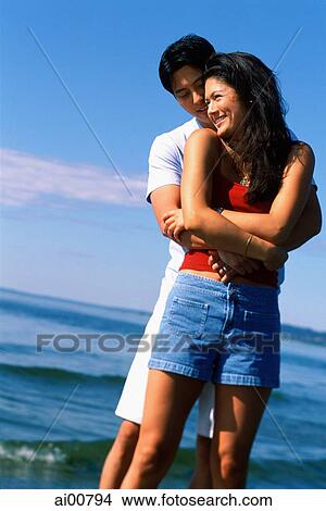 Picture - Young couple embracing on beach. Fotosearch