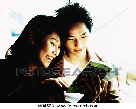 Young couple looking at book together. View Large Photo Image Stock Image - Young couple looking at book together.. Fotosearch
