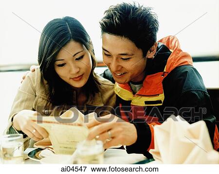 Stock Photo - Young couple looking at menu at restaurant.. Fotosearch
