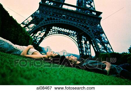 Young couple lying on grass, Eiffel Tower in background. (high-grained) View Large Photo Image Stock Photo - Young couple lying on grass, Eiffel Tower in background. (high-grained). Fotosearch