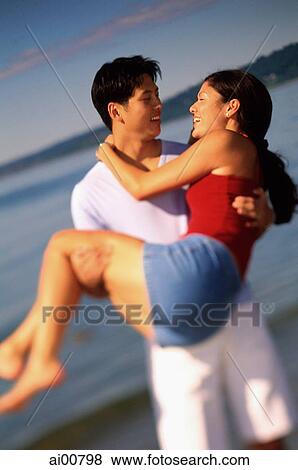 Young couple on beach, man carrying woman, talking View Large Photo Image Stock Photo - Young couple on beach, man carrying woman, talking. Fotosearch