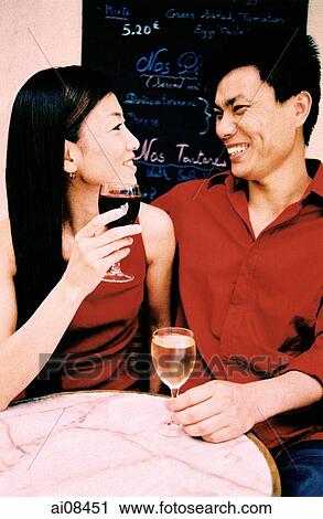 Young couple sitting at outdoor cafe holding wine glasses, smiling. (high-grained) View Large Photo Image Stock Image - Young couple sitting at outdoor cafe holding wine glasses, smiling. (high-grained). Fotosearch