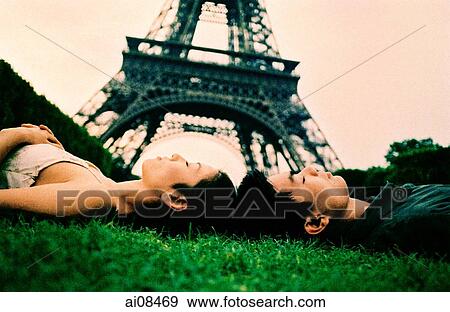 Stock Photo - Young couple sleeping on grass, Eiffel Tower in background. (high-grained). Fotosearch