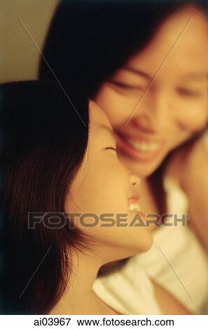 Stock Photo - Young girl laughing with mother in background. Fotosearch