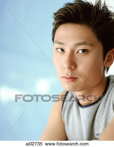 Stock Photography - Young man against blue background, portrait.. Fotosearch