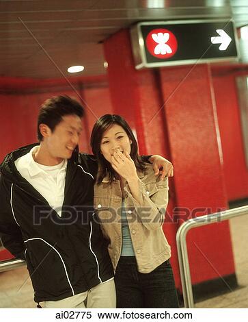 Stock Photography - Young man and woman talking in train station.. Fotosearch