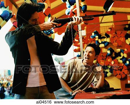 Young man cheering on friend at shooting gallery. View Large Photo Image Stock Photograph - Young man cheering on friend at shooting gallery.. Fotosearch
