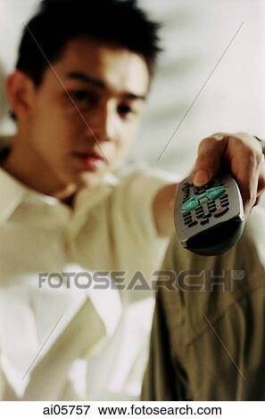 Stock Photo - Young man holding television remote. Fotosearch